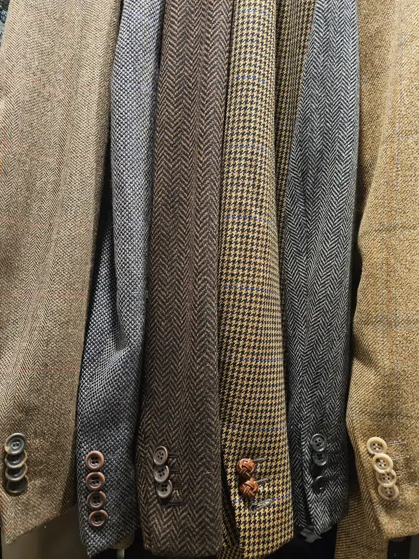 Eine Reihe Tweed- und Fischgrat-Sakkos auf der Stange